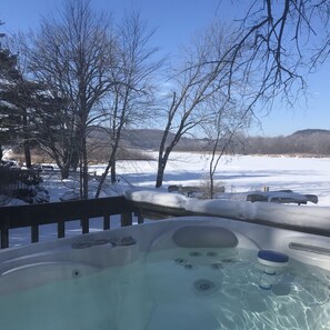 A hot tub with a clear view of a snowy landscape and trees in the background.