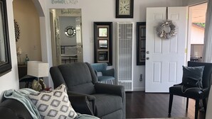 A living room with a dark leather sofa, a patterned rug, and a door with a wreath. - Beach house on the beach! (Ventura)