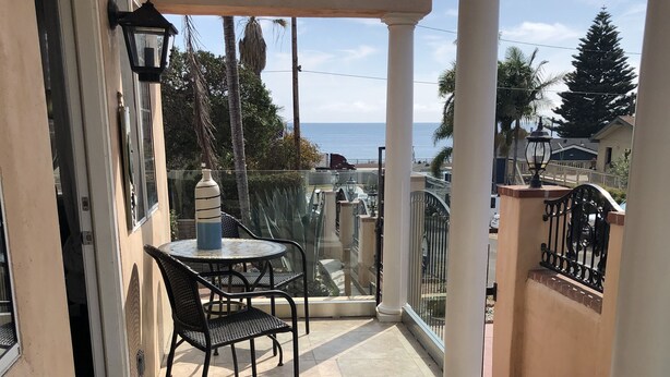 A covered outdoor seating area with a table and chairs, a decorative tiled floor, and a view of the sea. - Beach house on the beach! (Ventura)