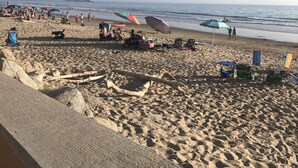 A beach with umbrellas, chairs, and a pier in the background. - Beach house on the beach! (Ventura)