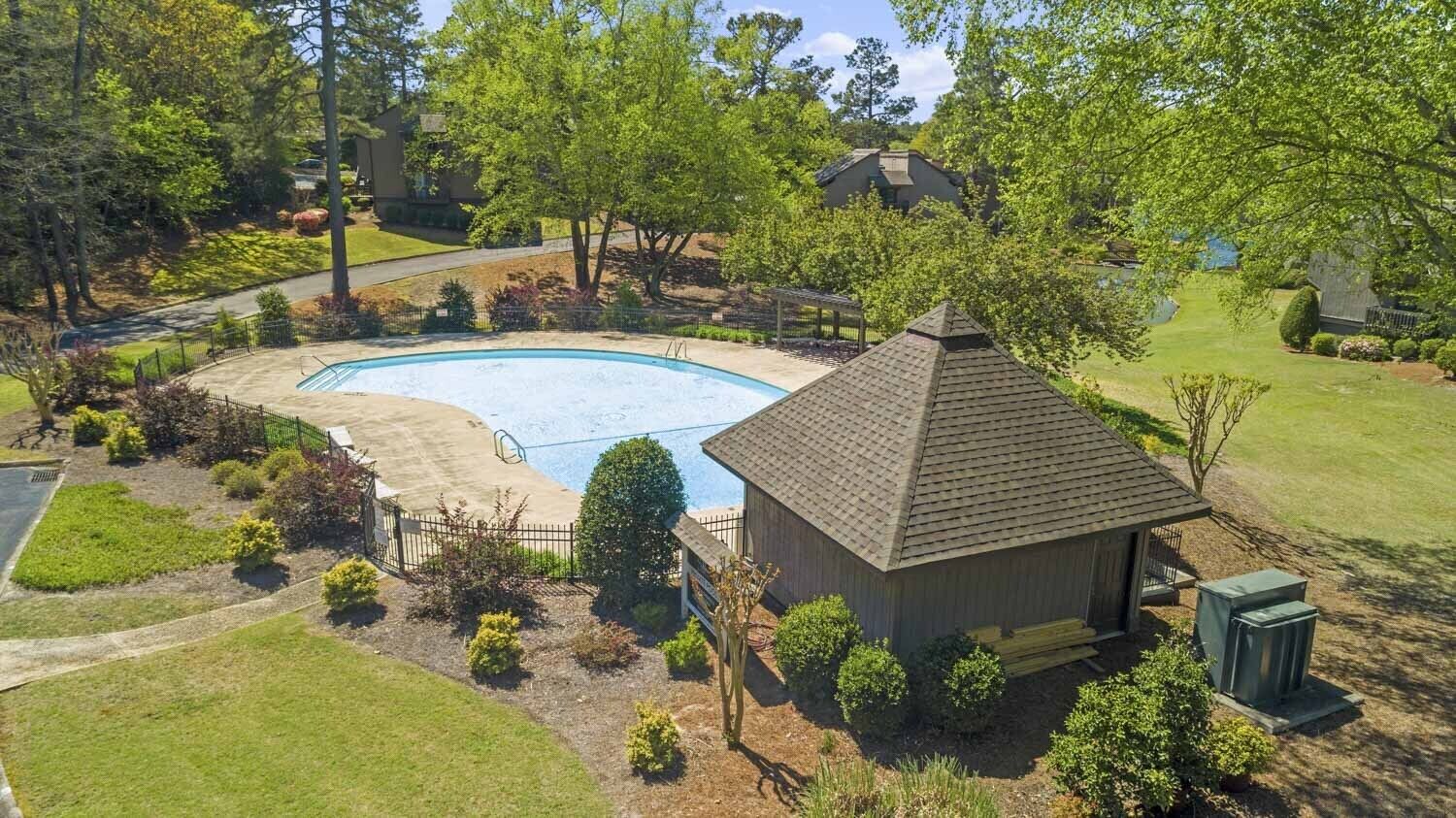Une propriété résidentielle dotée d’une piscine, d’un petit abri de jardin et d’une pelouse bien entretenue.