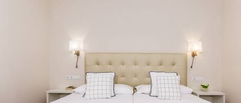 A hotel room with a double bed, two bedside tables, and wall-mounted lamps.