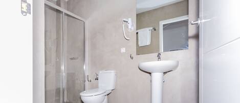 Une salle de bain avec une douche à parois de verre, des toilettes et un lavabo.