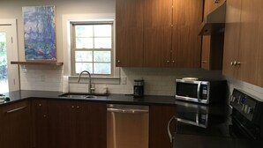 A modern kitchen with wooden cabinets, a stainless steel dishwasher, a microwave, and a coffee maker. - Sanitized! Spacious Ranch Close To Gsp Airport, Greenville, Greer set on acres.  (Greenville)