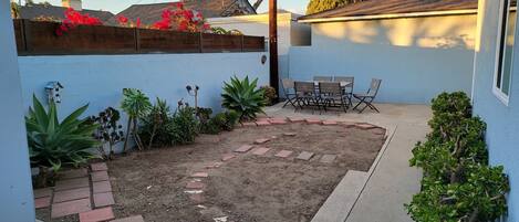A backyard with a patio, a small table and chairs, and various plants.