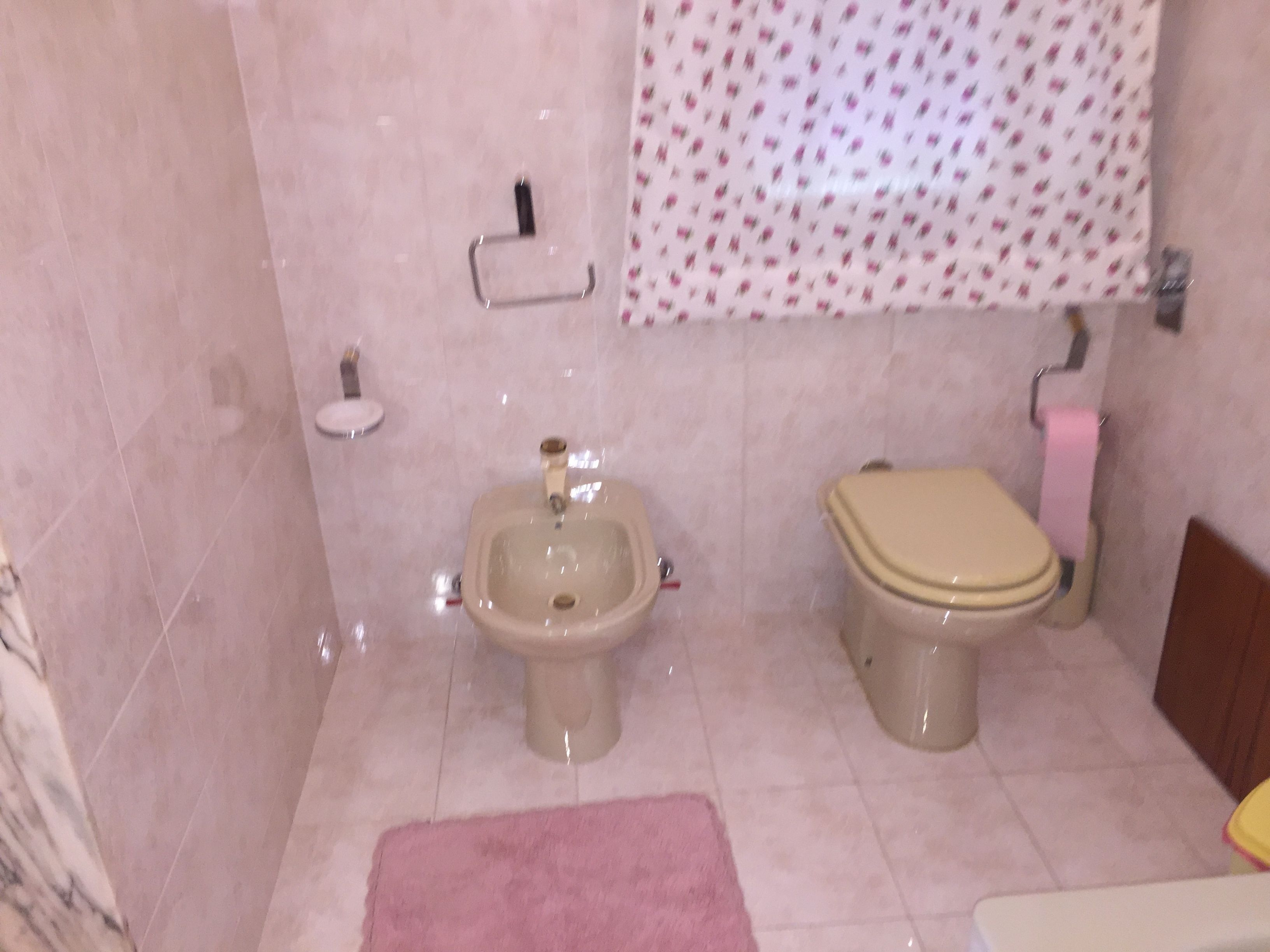 Un baño con bidé, inodoro y una alfombra rosa.