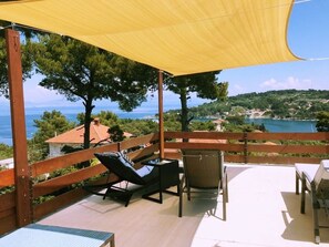 A terrace with a yellow canopy, lounge chairs, and a table.