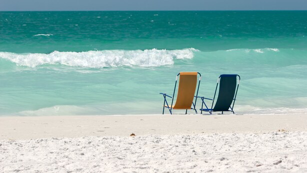 Two beach chairs facing the ocean with waves crashing onto the shore. - Bayfront 2 Bedroom with Private Dock and Beach Access Riley's Retreat (Treasure Island)