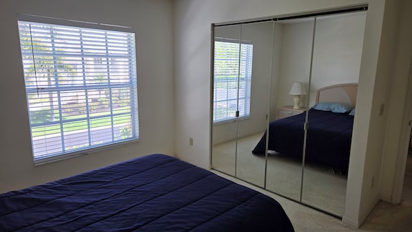 Un dormitorio con una cama, una mesita de noche, una lámpara y un armario corredero.