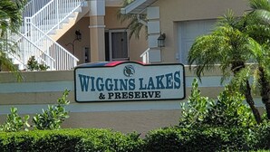 A sign for Wiggins Lakes & Preserve with a staircase and palm trees in the background. - 300 OFF APRIL TO NOVEMBER (Naples)