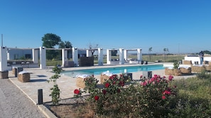 A pool area with a pergola, seating, and hay bales. - Masseria Fontana di Vite (Matera)