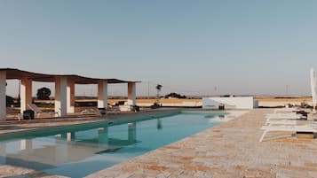 Una piscina al aire libre de temporada, sombrillas