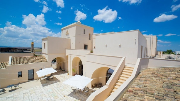 Una terrazza sul tetto con posti a sedere all'aperto, una scala e un edificio con archi e una torre.