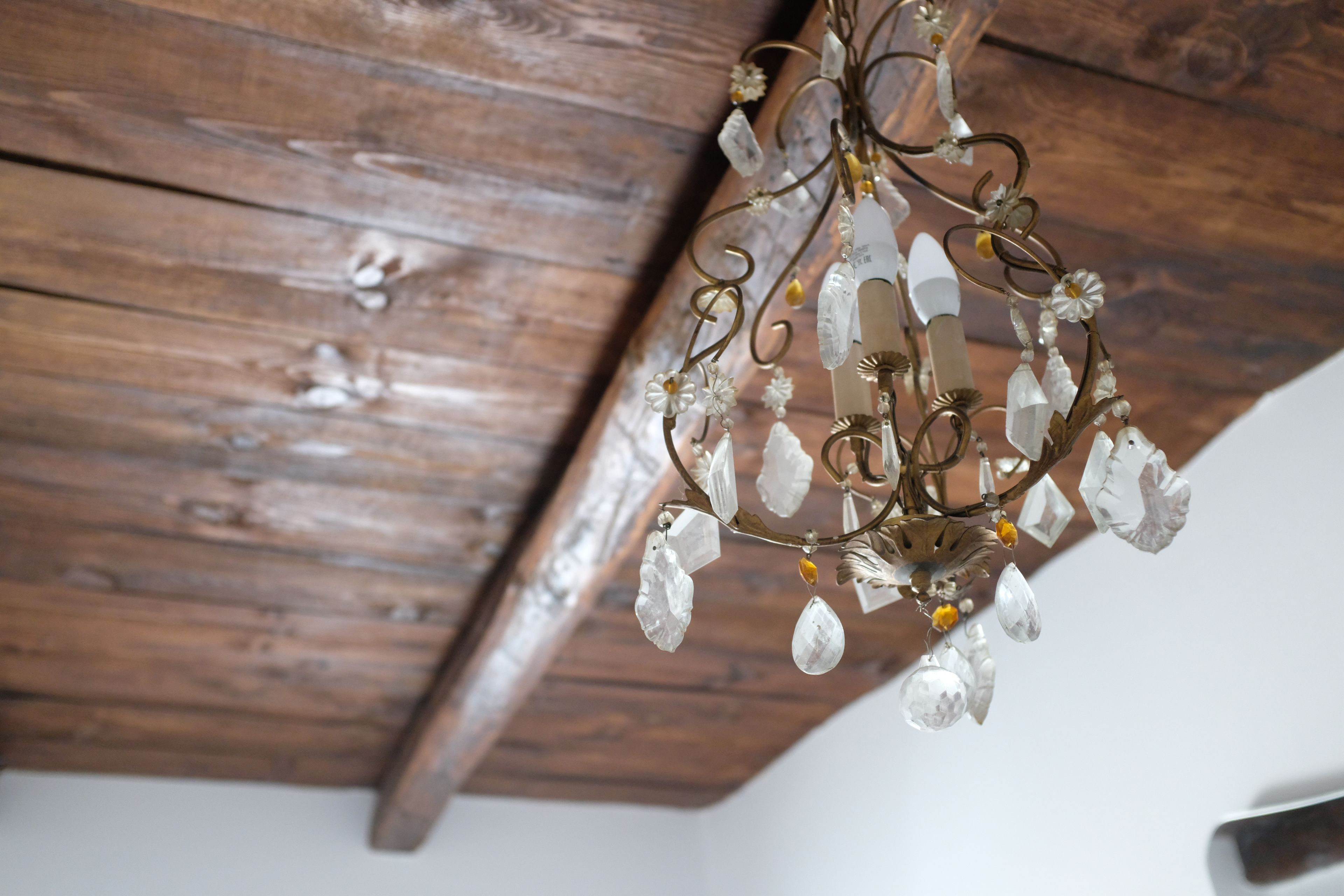 A chandelier with crystal decorations hanging from a wooden ceiling.