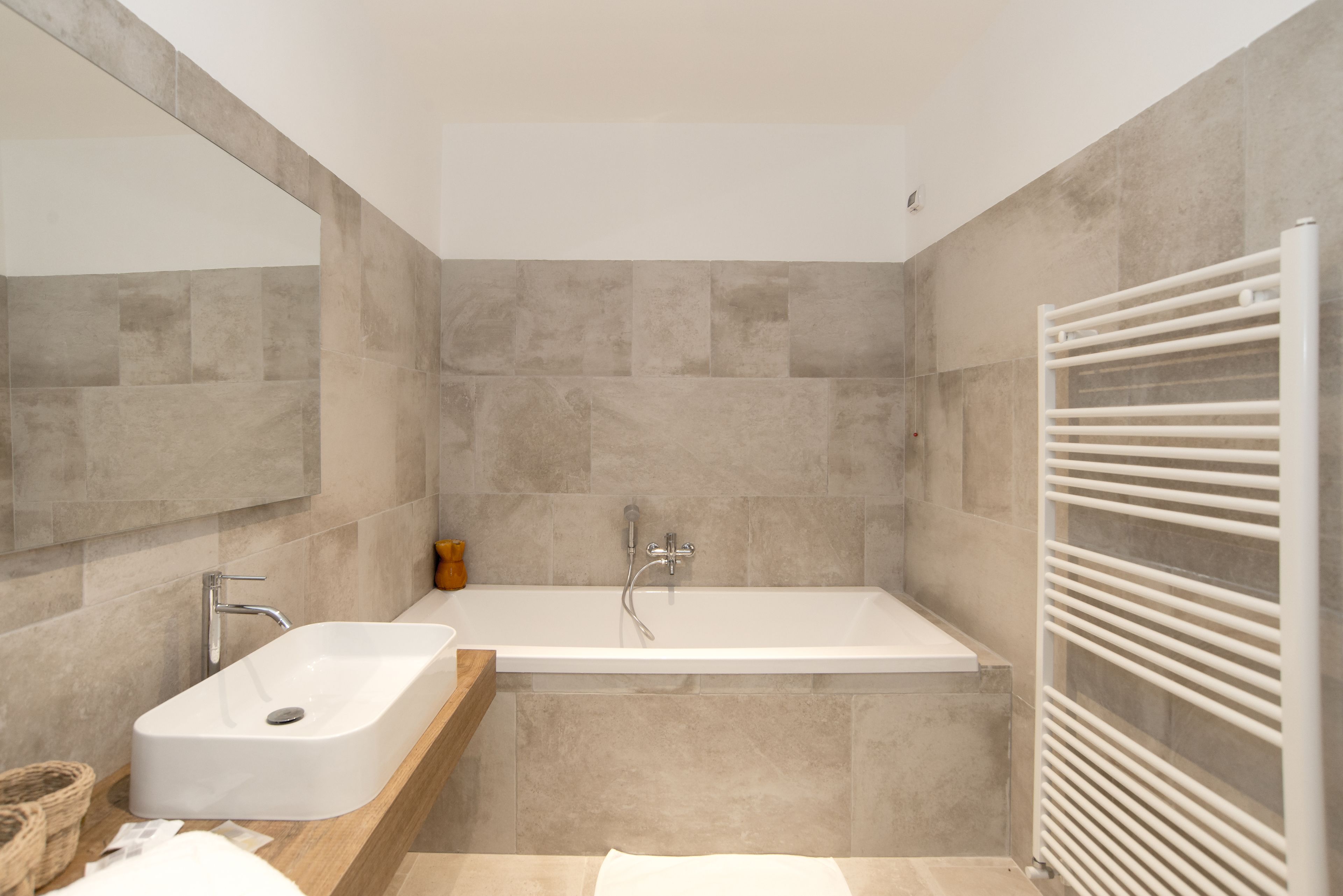 Ein modernes Badezimmer mit einer rechteckigen Badewanne, einem Waschbecken und einem Spiegel.