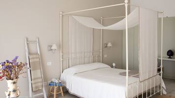 A four-poster bed with a canopy, a bedside table with a lamp, a small stool, and a vase with flowers.