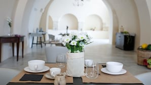 Una tavola imbandita con tazze, piattini e un vaso di fiori bianchi.