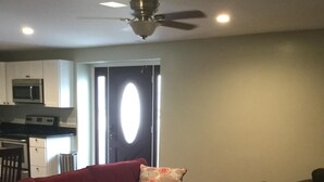 A living room with a red sofa, a patterned pillow, a small wooden table, and a ceiling fan. - comfort, luxury, privacy (Amherst)