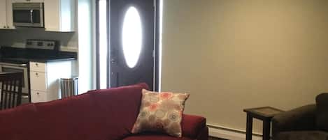 A living room with a red sofa, a patterned pillow, a small wooden table, and a ceiling fan.