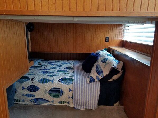 Una cabaña pequeña y de madera con literas, un ventanal y una estantería empotrada.