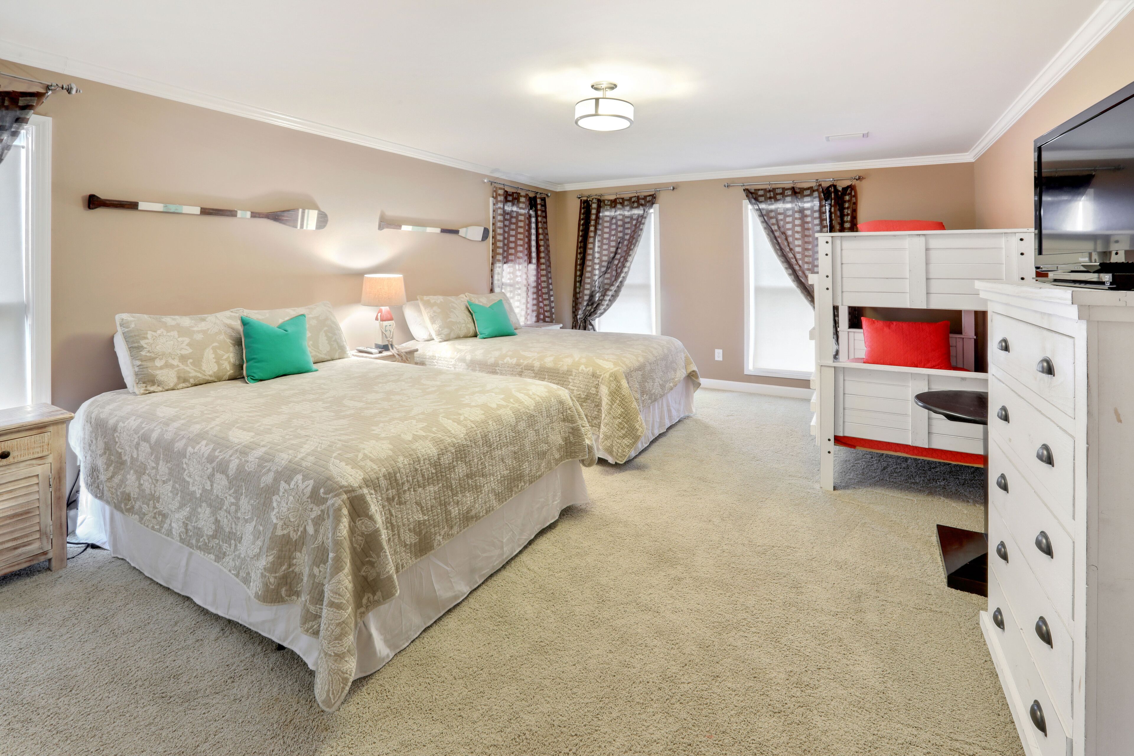Un dormitorio con dos camas, televisor, cómoda y cortinas.