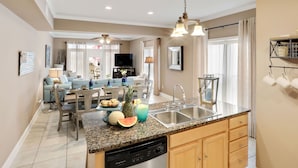 A modern kitchen with granite countertops, a dishwasher, and a dining area with a table and chairs.