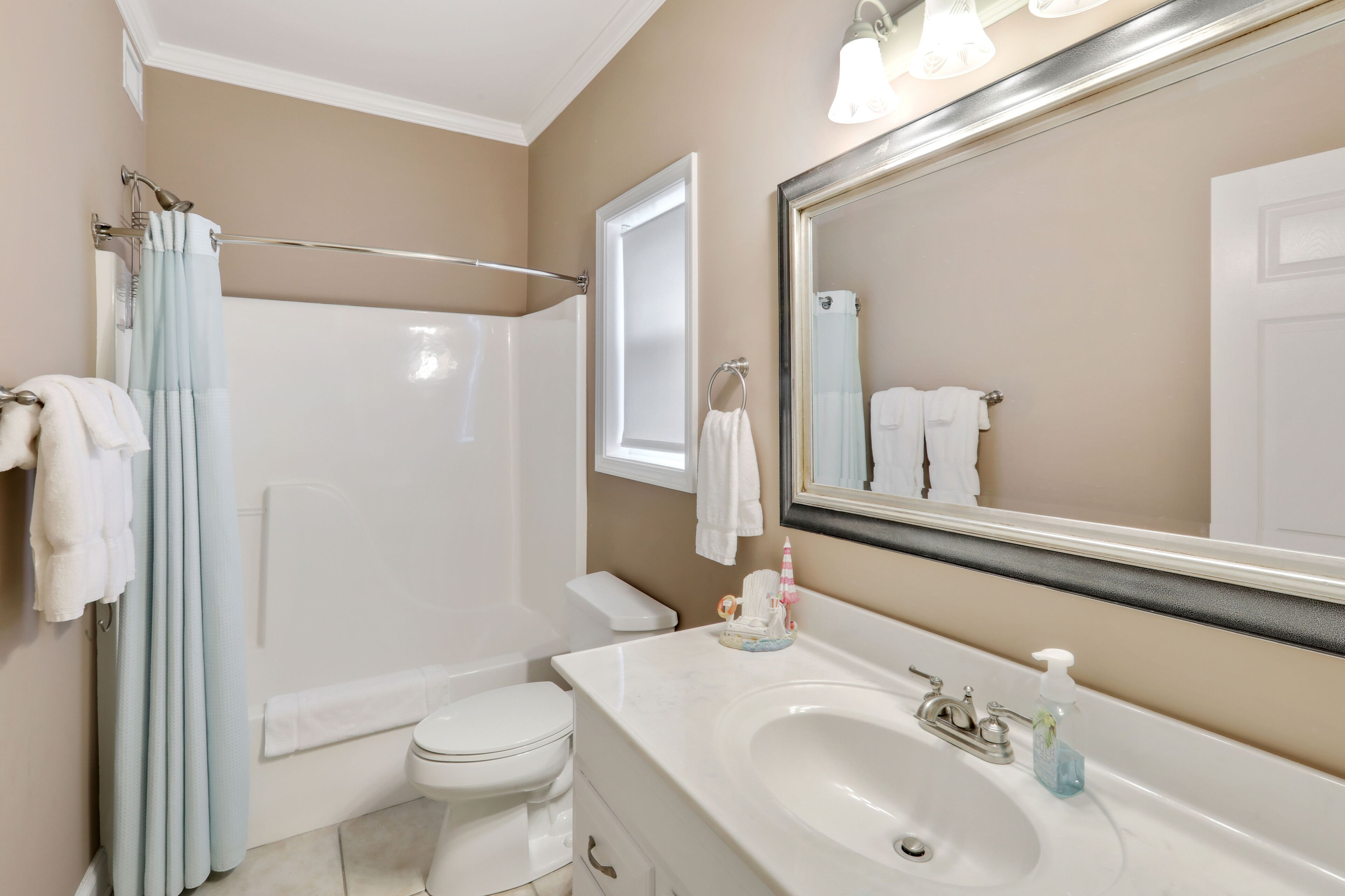 A bathroom with a bathtub, toilet, sink, and a large mirror.