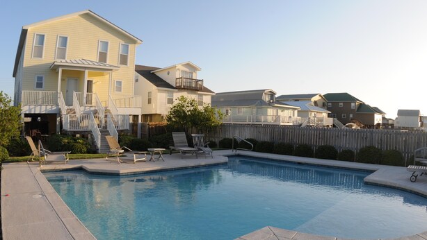 A swimming pool with lounge chairs and a wooden fence.