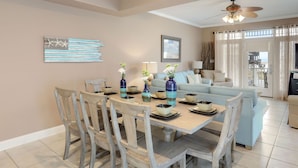 A dining area with a wooden table and chairs, a light blue sofa, and a ceiling fan.
