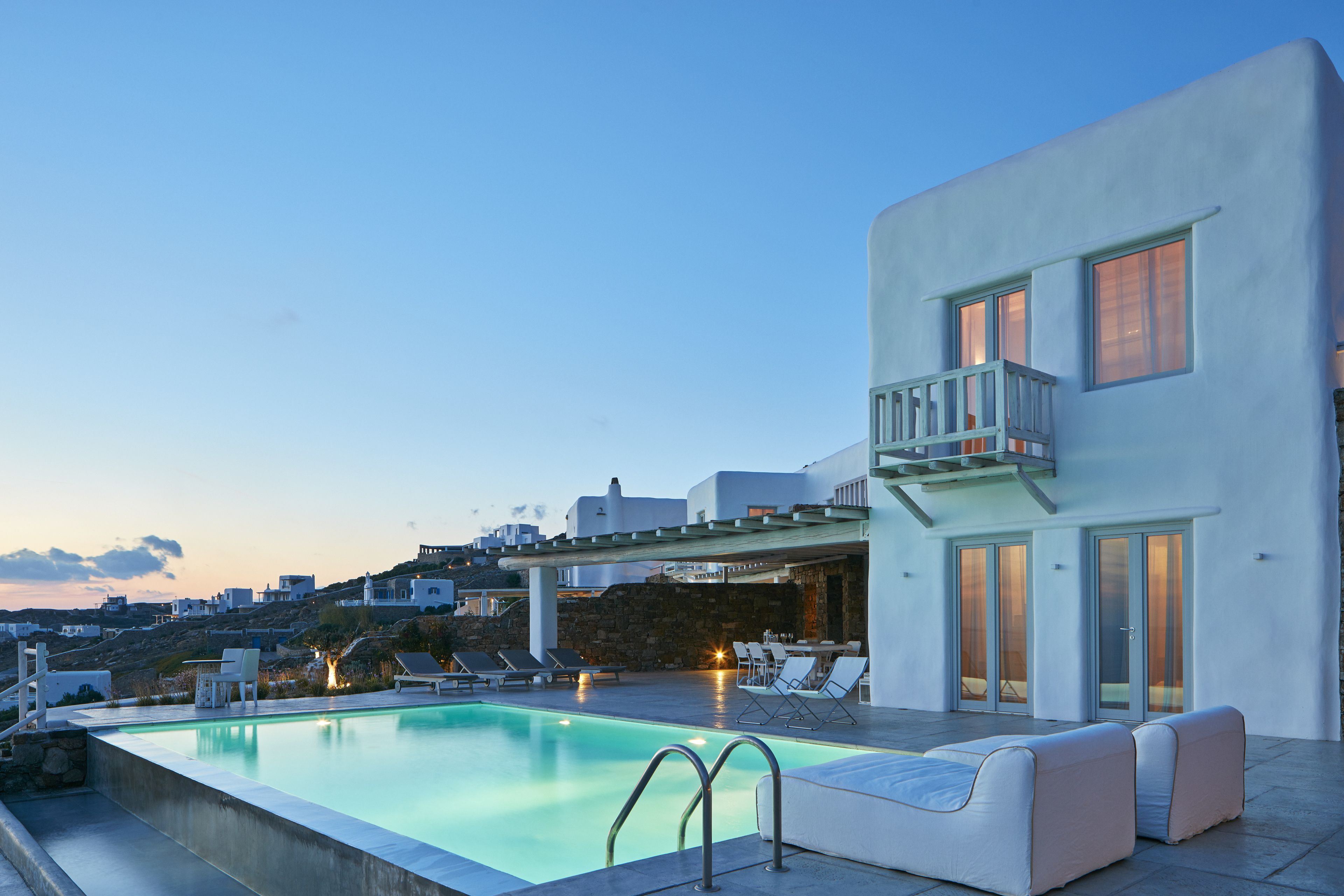 Ein moderner Poolbereich mit Liegestühlen und einem Gebäude mit großen Fenstern und einem Balkon.