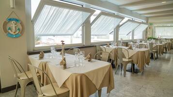A restaurant with multiple tables set for dining, large windows, and a 'Welcome' sign on the wall.