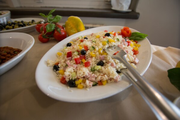 A plate of rice salad with various vegetables and ham, accompanied by a fork. - Hotel Il Settebello (Cecina)