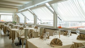 A restaurant with multiple tables set for dining, large windows, and a view of the city.