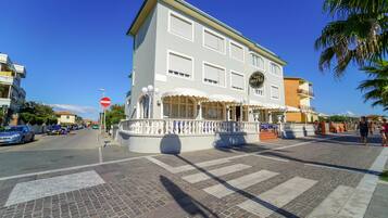 Ein Hotel mit weißer Fassade, zahlreichen Fenstern und einem Balkonbereich.