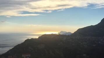 A coastal landscape with a mountain in the background and a village in the foreground.