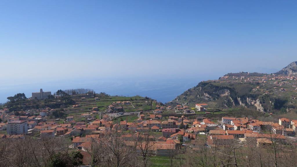 A coastal town with terraced houses, a prominent building on the left, and a clear view of the sea.