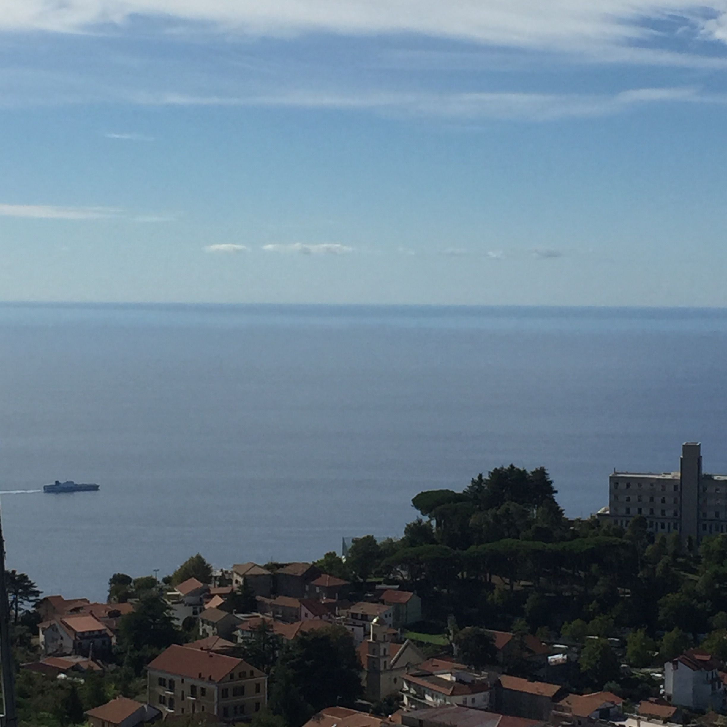 A coastal town with a view of the sea and a ship in the distance.