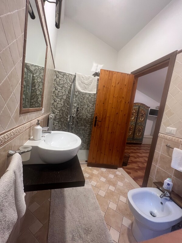 Un baño con un lavamanos grande, un bidé, un espejo y una puerta de madera.