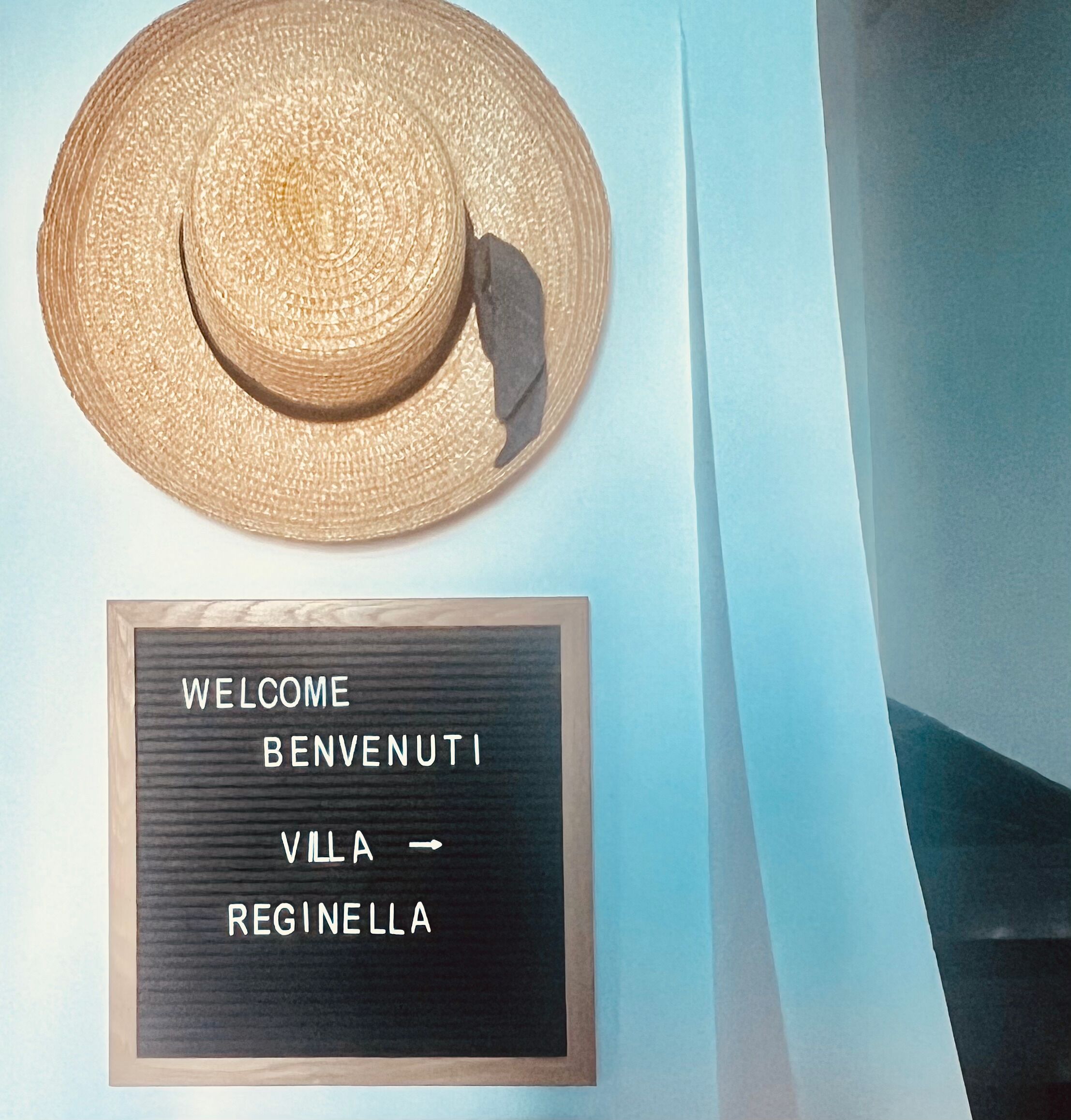 A straw hat and a welcome sign with multilingual greetings.