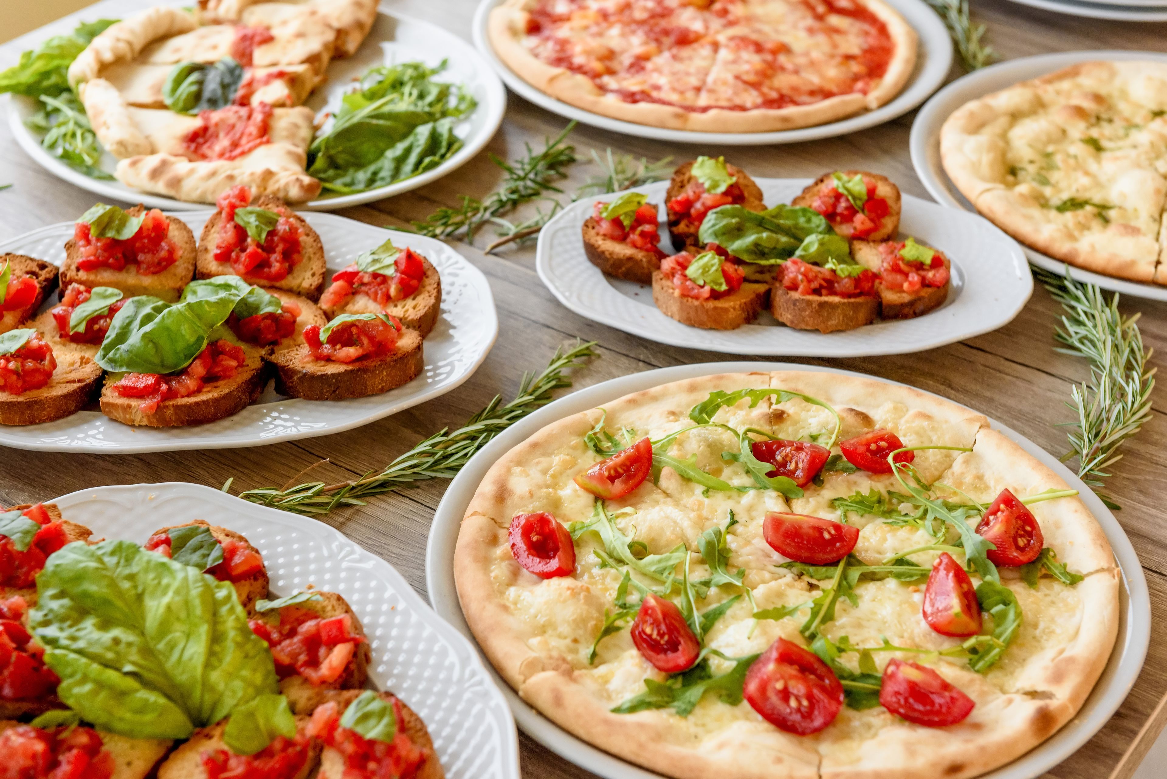 Variedad de pizzas y bruschetta en platos.