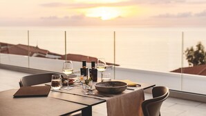 Mesa dispuesta para cenar con vista al mar al atardecer.