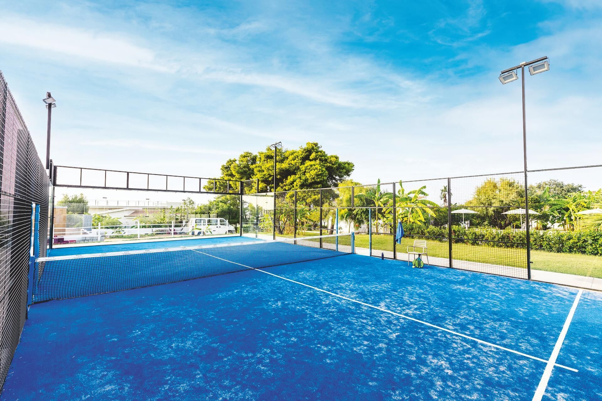 Piscina esterna con recinto a rete, immersa nel verde sotto un cielo sereno.