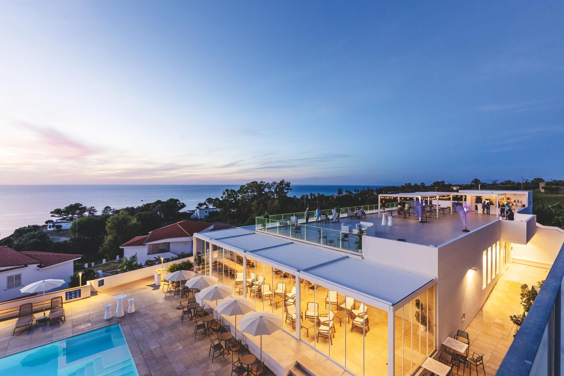 Une terrasse sur le toit avec une piscine, des espaces de détente en plein air et une vue sur la mer.