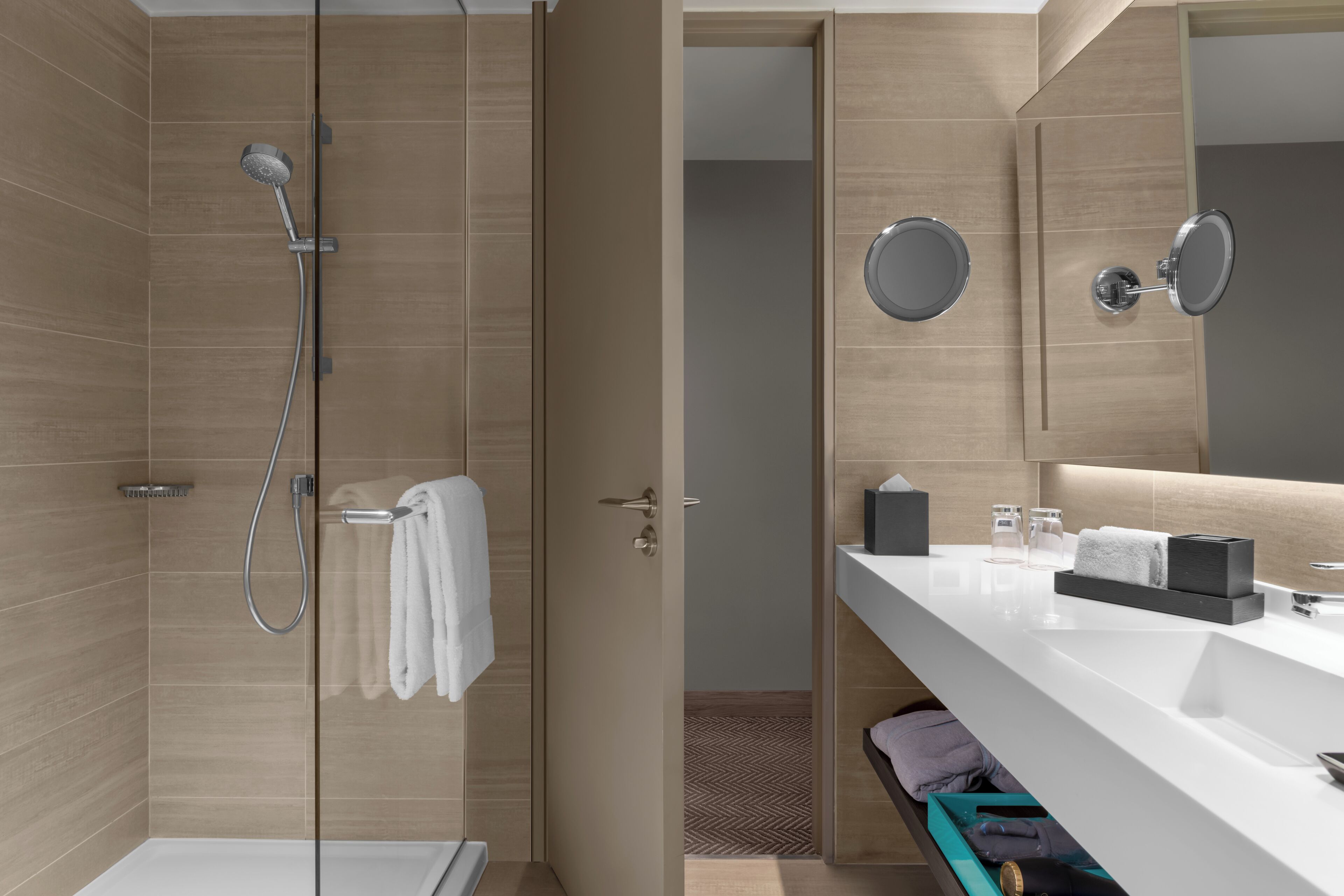 Un baño moderno con ducha, tocador con espejo y un perchero para toallas.