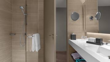 Un baño moderno con ducha, tocador con espejo y un perchero para toallas.