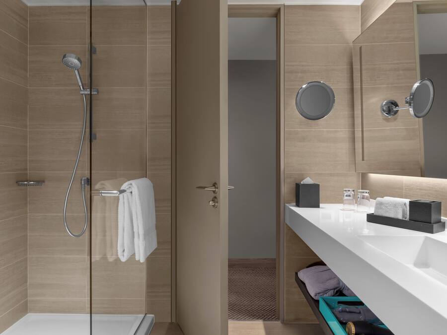 Un baño moderno con ducha, tocador con espejo y un perchero para toallas.