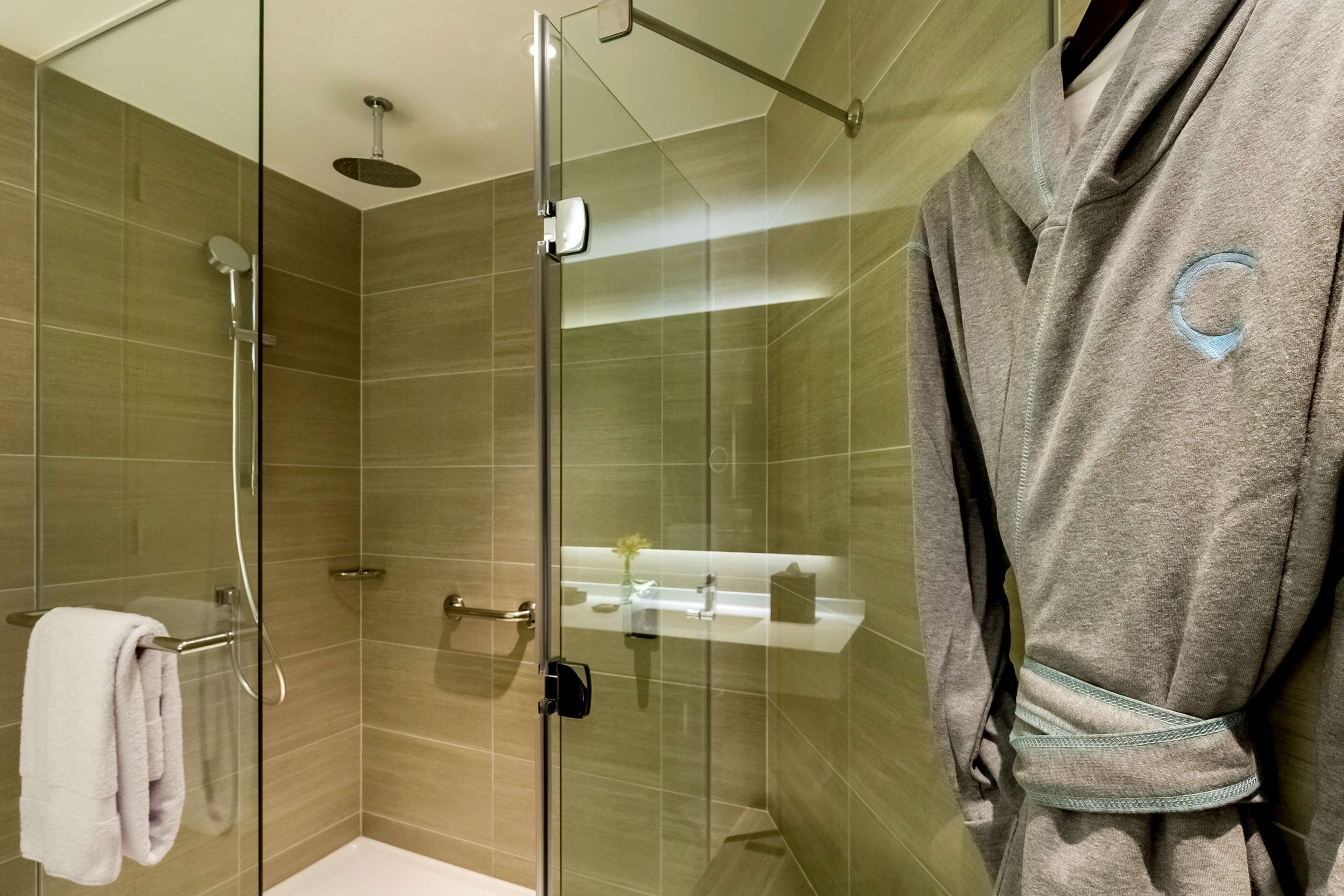 A modern bathroom with a glass shower enclosure, a towel rack, and a vanity with a mirror.