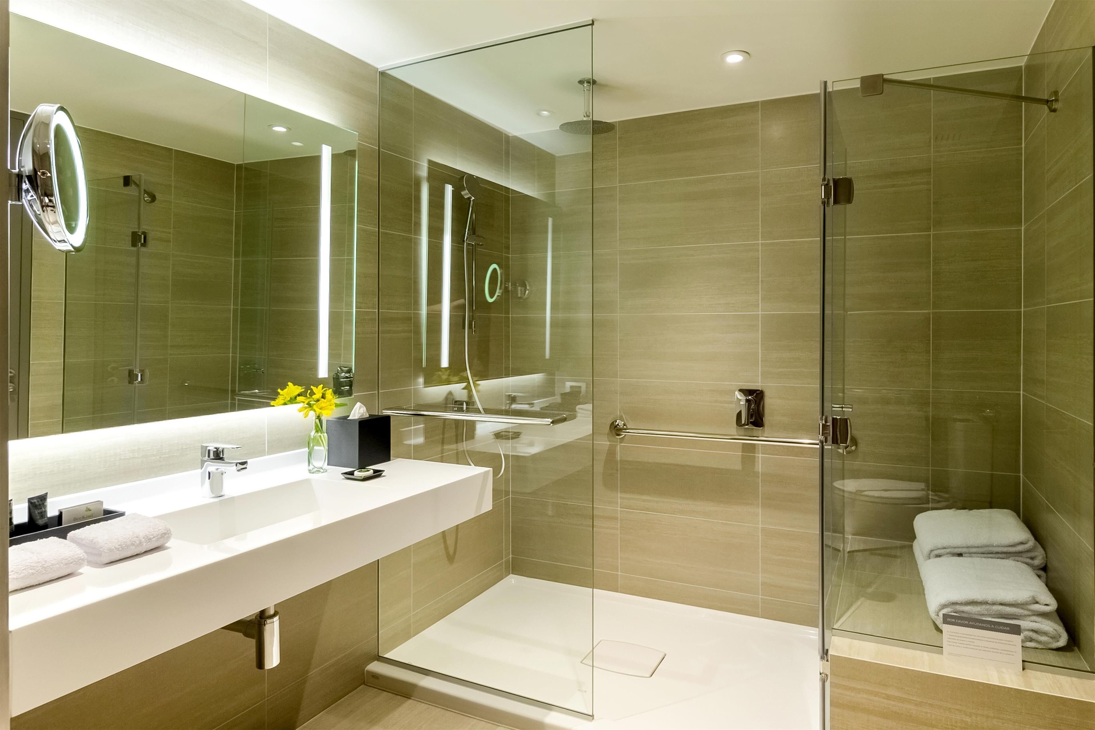 A modern bathroom with a glass-enclosed shower, a large mirror, and a white vanity.
