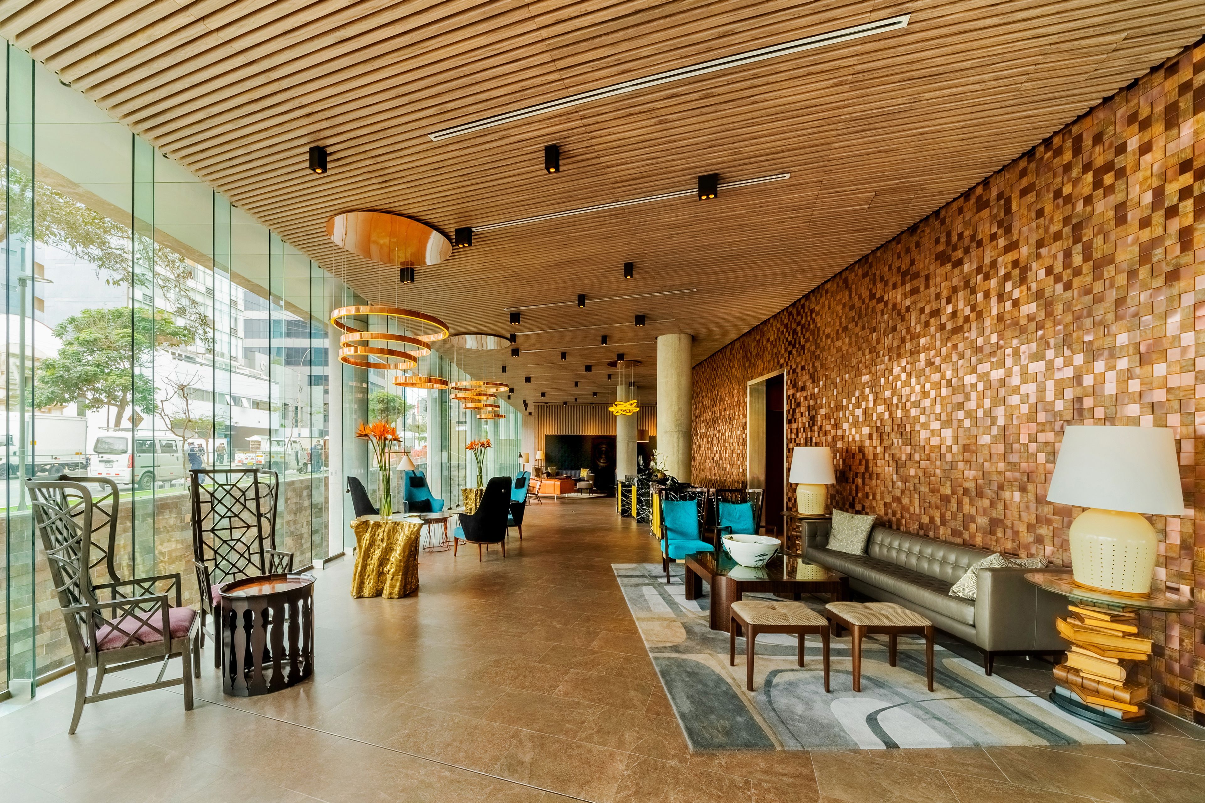 Un vestíbulo espacioso con techo de madera, mobiliario moderno y amplias ventanas que ofrecen vistas al exterior.