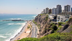 Un paisaje urbano costero con playa, carretera y edificios altos.